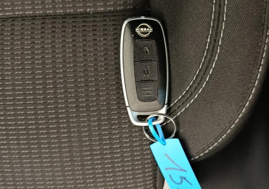 Clé de voiture Nissan posée sur un siège tissu noir avec couture blanche, intérieur du Nissan Qashqai e-Power 2024.