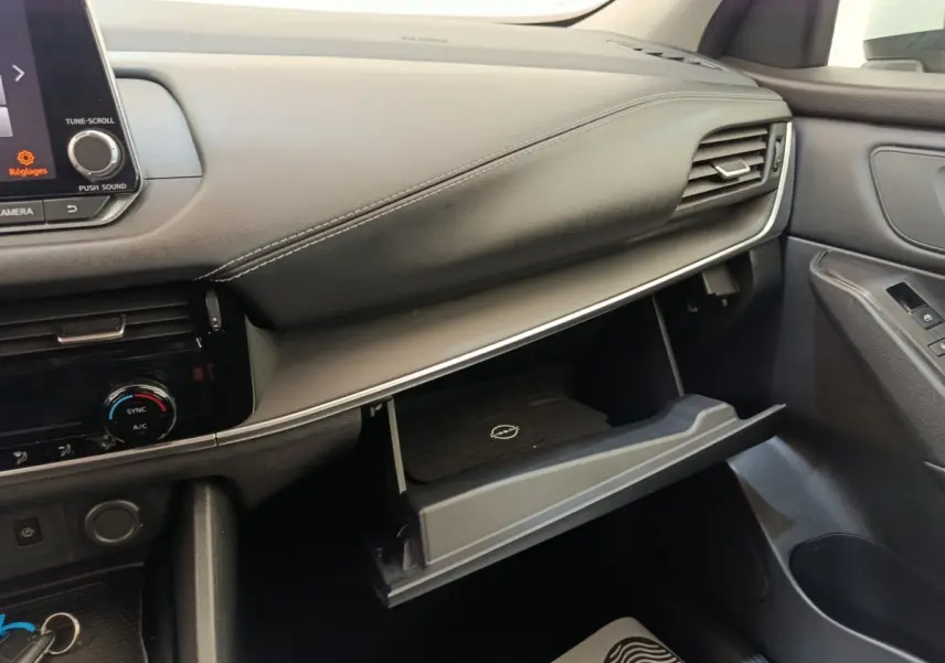 Intérieur côté passager du Nissan Qashqai e-Power 2024, tableau de bord gris avec boîte à gants ouverte.