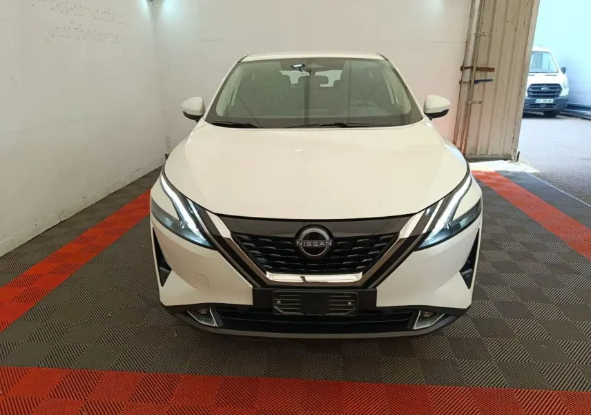 Vue frontale d'un Nissan Qashqai e-Power blanc, avec calandre noire et phares LED allumés, dans un garage.