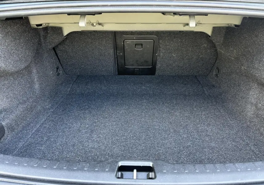 Coffre spacieux et vide de la Volvo S60 B4 2024 en gris Thunder, vue intérieure depuis l'arrière ouverte.