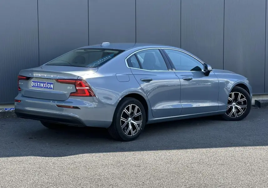 Volvo S60 B4 gris Thunder vue 3/4 arrière droit avec jantes alliage 17 pouces et contours de fenêtres chromés.