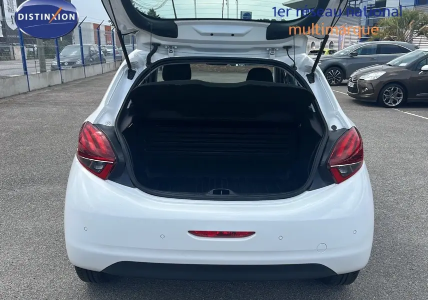 Vue arrière ouverte d'une Peugeot 208 blanche Banquise 2020, coffre dégagé et feux arrière rouges visibles.