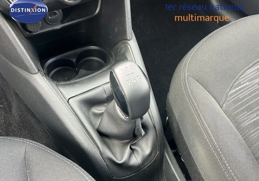 Gros plan sur la console centrale d'une Peugeot 208 blanche banquise, mettant en valeur le levier de vitesse manuel et les sièges noirs.