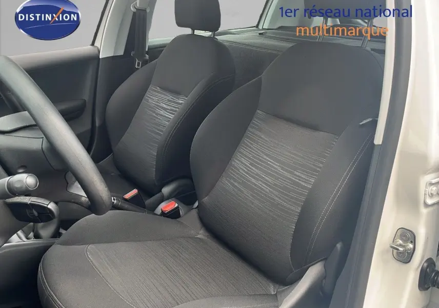Intérieur de la Peugeot 208 blanche, vue côté conducteur, mettant en valeur les sièges noirs en tissu.