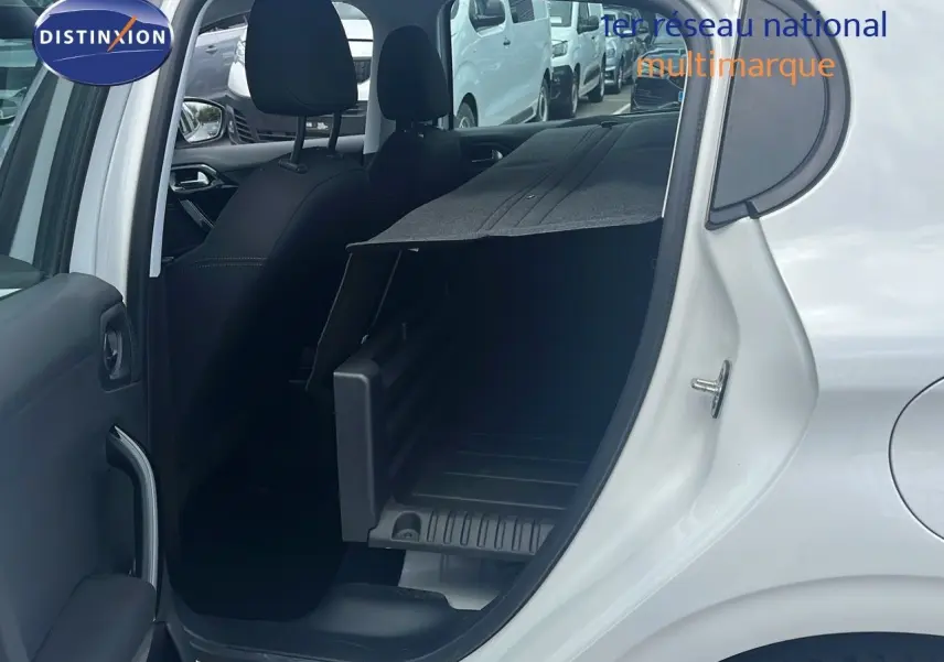Vue côté gauche arrière d'une Peugeot 208 blanche banquise 2020 avec siège arrière rabattable et coffre aménagé.