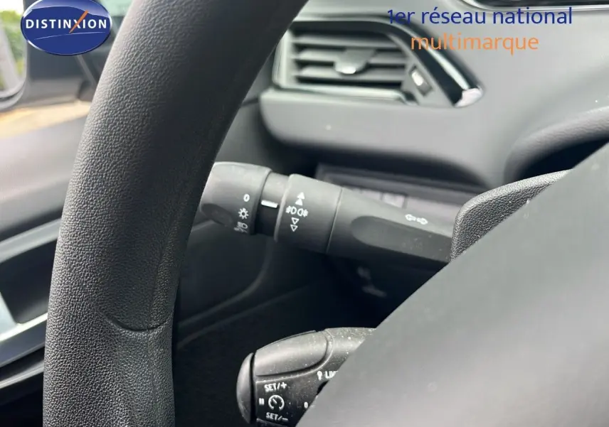 Gros plan sur le volant et les commandes au volant d'une Peugeot 208 blanche, version Société 2020, intérieur noir.