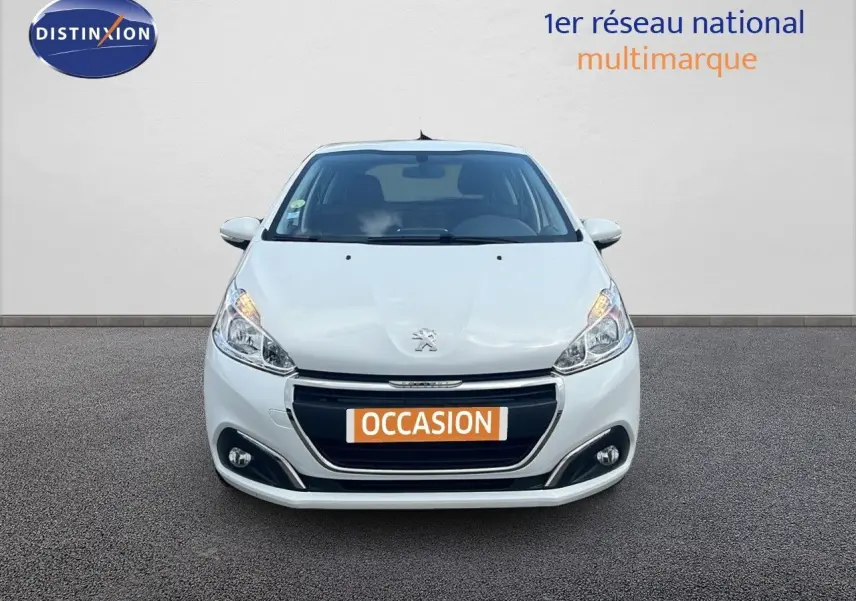 Peugeot 208 blanc banquise vue de face, mettant en valeur sa calandre et ses phares allumés.