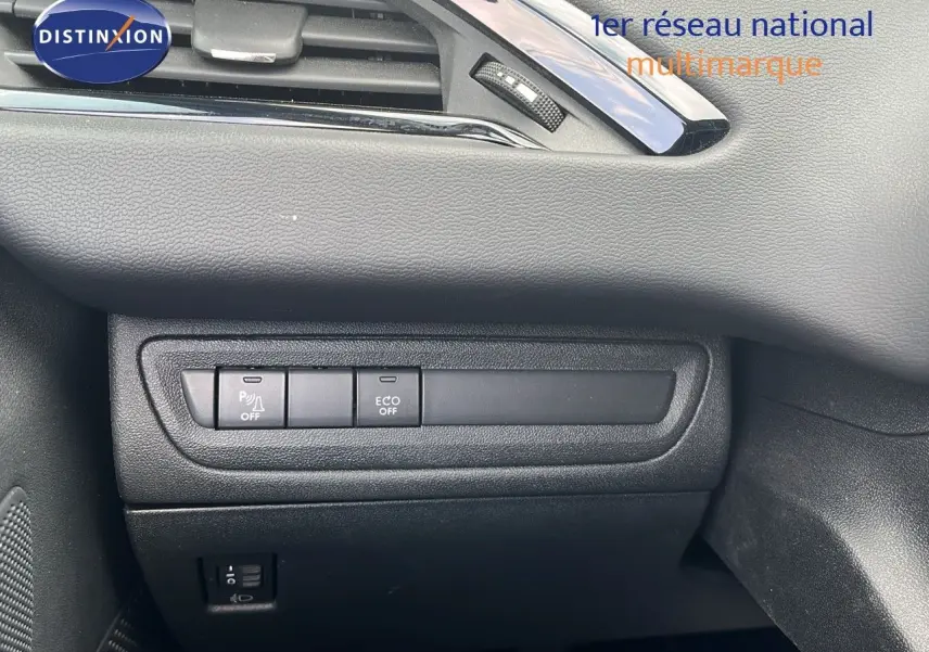 Détail intérieur côté gauche du tableau de bord de la Peugeot 208 blanche montrant les boutons ECO et parking.