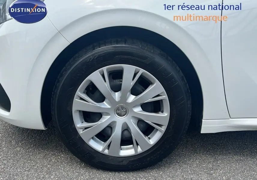 Gros plan sur la roue avant gauche blanche d'une Peugeot 208 Societe 2020 avec enjoliveur argenté et logo lion central.