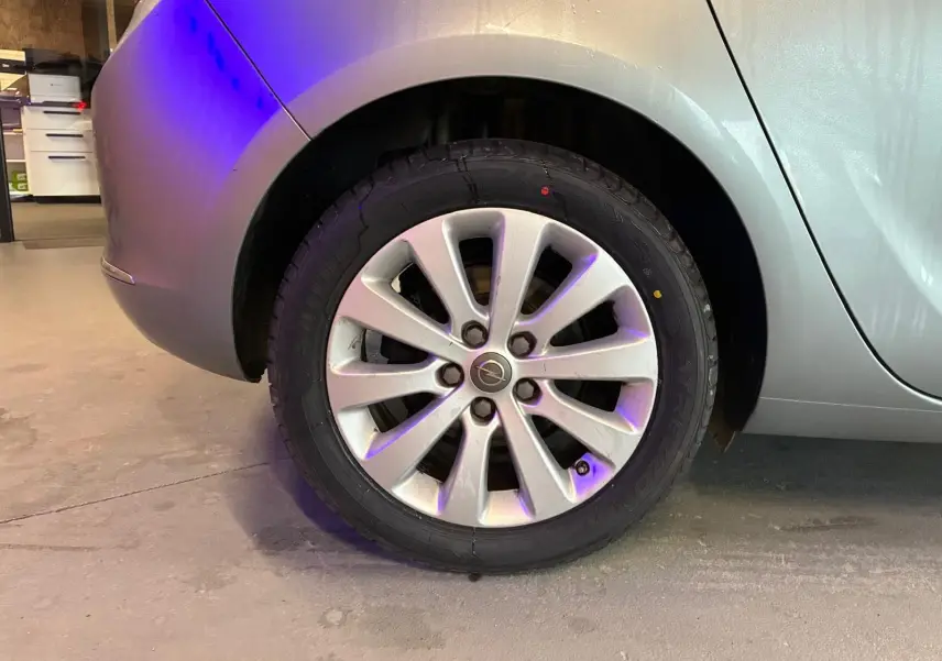 Gros plan sur la roue arrière droite grise d'une Opel Astra 1.6 CDTI 110 diesel de 2015 en intérieur.