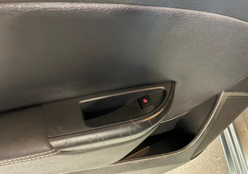 Détail de la poignée intérieure de porte côté gauche d’une Opel Astra gris 2015 avec bouton de verrouillage électrique.