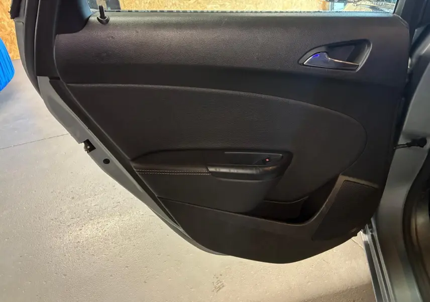Vue intérieure de la porte arrière droite grise d'une Opel Astra 2015, avec poignée et commande de fenêtre noire.