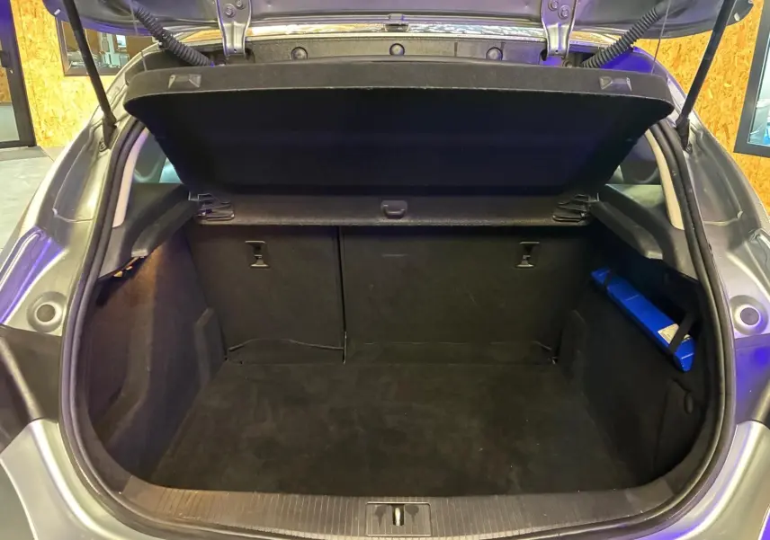 Coffre ouvert d'une Opel Astra gris 2015, vue arrière montrant l'espace de chargement vide et la tablette arrière relevée.
