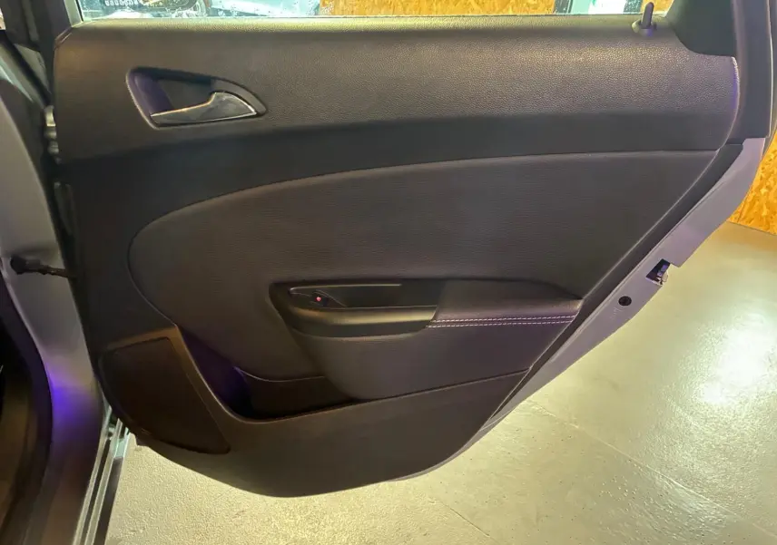 Vue rapprochée de la porte arrière gauche noire de l’Opel Astra 1.6 CDTI 110 gris, avec poignée intérieure et haut-parleur intégré.