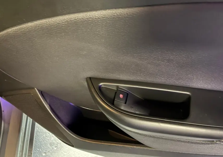 Gros plan sur la commande de lève-vitre côté gauche de la porte intérieure d’une Opel Astra gris 2015.