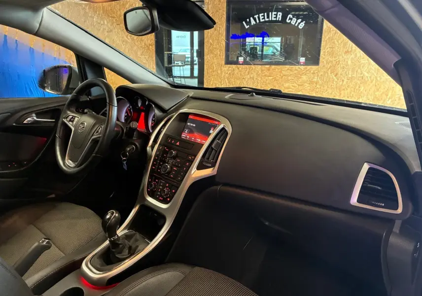 Vue intérieure côté conducteur de l’Opel Astra gris 2015, avec tableau de bord et console centrale rétroéclairée.