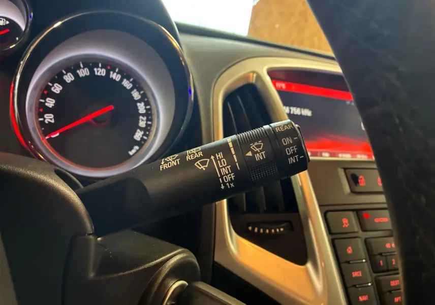 Gros plan sur le commodo d’essuie-glace à gauche du volant dans l’habitacle gris d’une Opel Astra 2015.