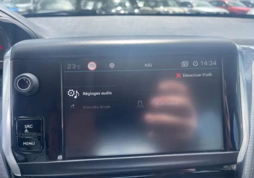 Écran tactile central du tableau de bord de la Peugeot 208 blanc perle, affichant les réglages audio en plein jour.