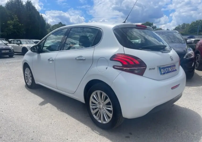 Peugeot 208 blanc perle vue 3/4 arrière droit, avec jantes alliage et feux arrière distinctifs rouges.