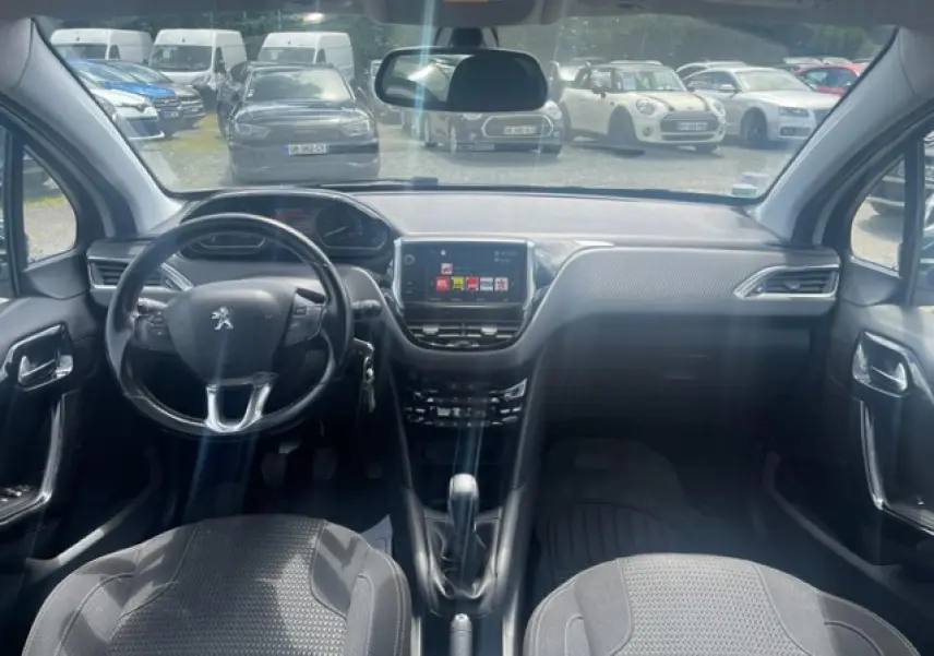 Vue intérieure avant de la Peugeot 208 blanche perle, montrant le volant compact multifonction et l’écran tactile central.