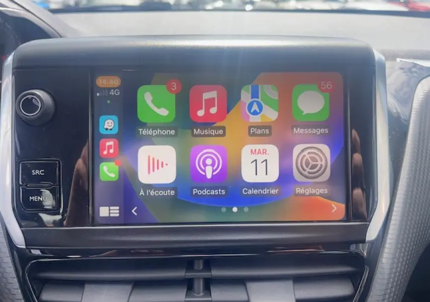Écran tactile central avec interface CarPlay dans l’habitacle d’une Peugeot 208 blanche perle, vue de face rapprochée.