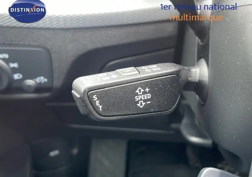 Gros plan sur la commande de régulateur de vitesse à gauche du volant dans l'Audi Q2 noir mito metal 2023.