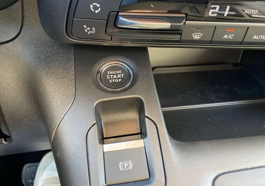 Détail intérieur du tableau de bord du Citroën Berlingo 2025 montrant le bouton start/stop et la commande de frein à main électrique.