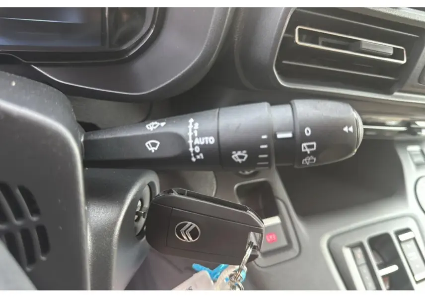 Gros plan sur la commande d'essuie-glace et la clé de contact du Citroën Berlingo 2025, intérieur noir.