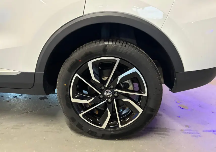 Gros plan sur la roue arrière droite du MG ZS blanc 2022, avec jante alliage noire et argentée au design moderne.