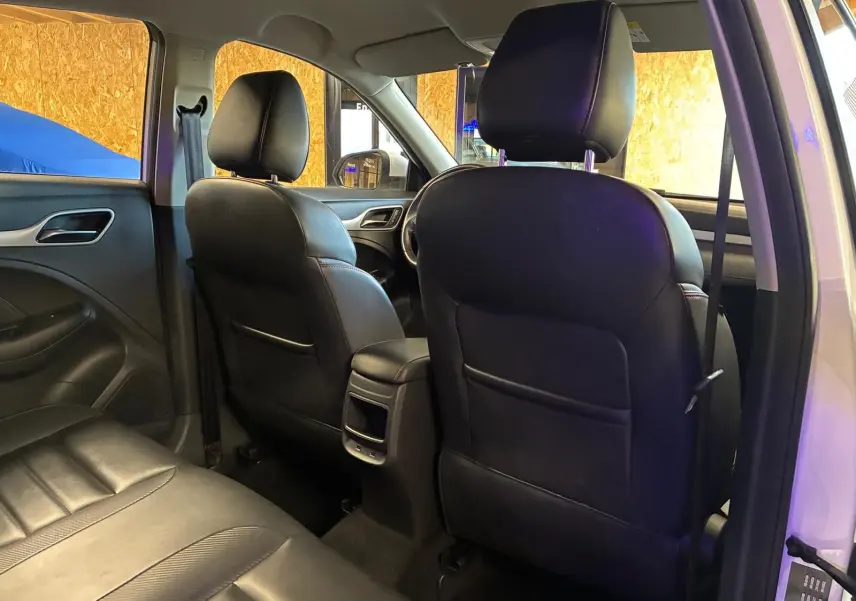 Vue intérieure arrière du MG ZS blanc 2022, montrant les sièges avant en cuir noir et la banquette arrière.