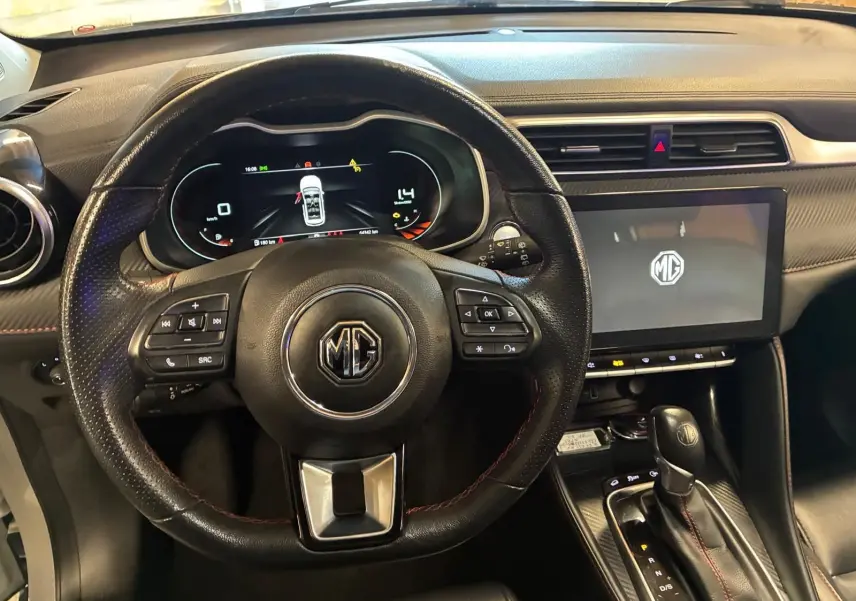 Vue intérieure centrée sur le volant noir perforé et l'écran tactile du tableau de bord du MG ZS blanc 2022.