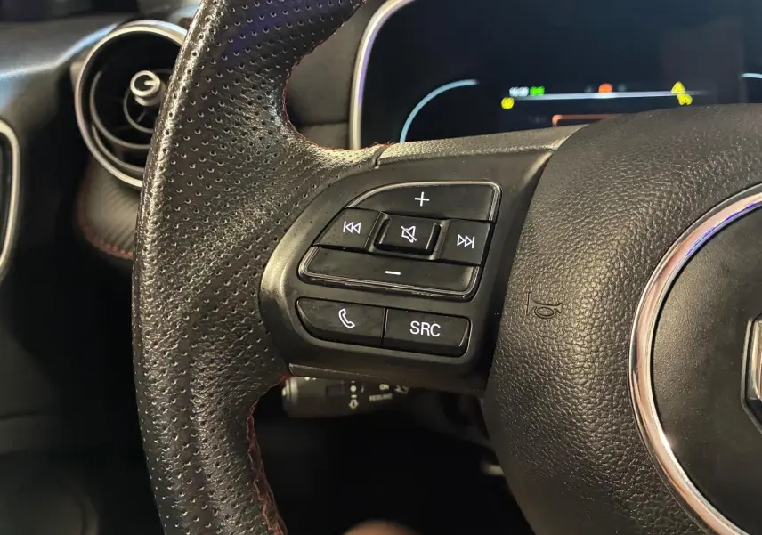 Gros plan sur le côté gauche du volant en cuir noir perforé du MG ZS blanc, avec commandes audio et téléphone intégrées.