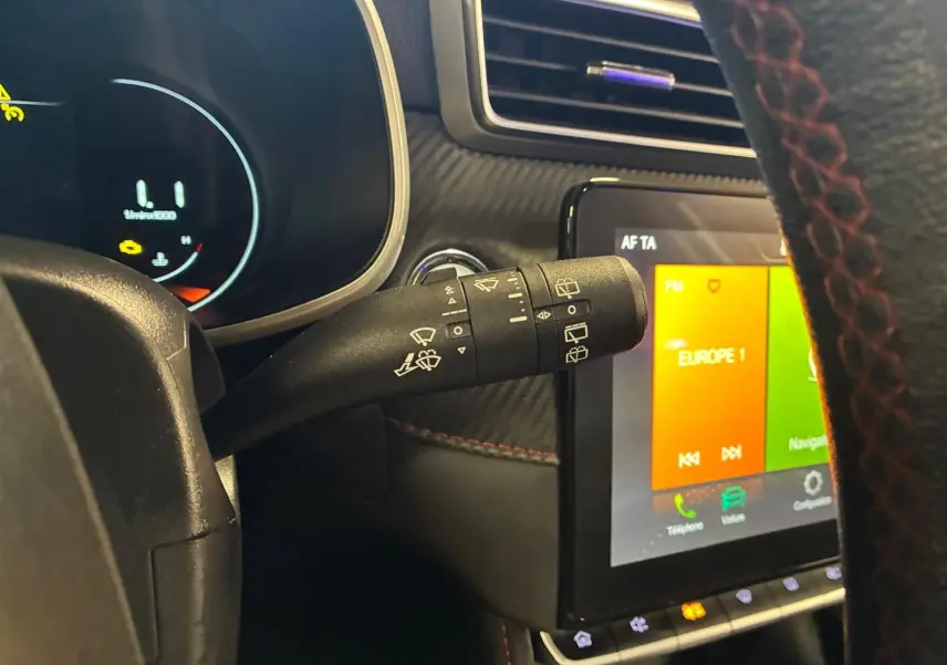 Gros plan sur la commande d’essuie-glace à gauche du volant dans l’habitacle noir du MG ZS blanc, avec écran tactile visible.