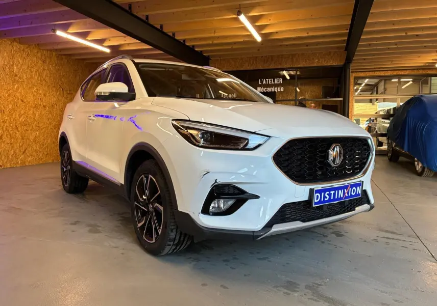 Vue 3/4 avant droite du MG ZS blanc 2022 dans un garage, avec calandre noire et jantes alliage noires.