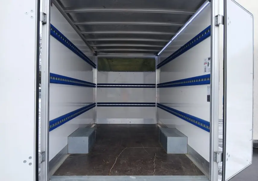 Vue intérieure arrière du Renault Master blanc 2023 avec caisse de chargement vide et rails bleus sur les parois.