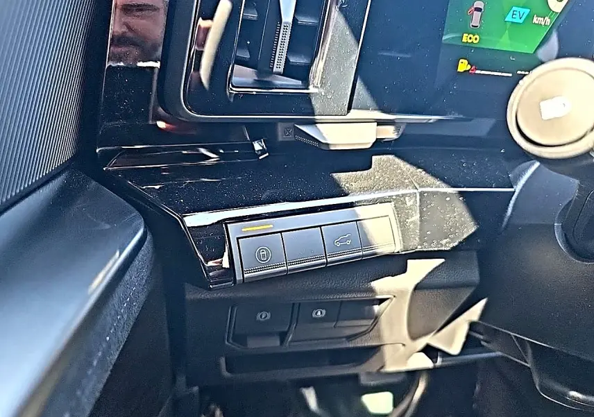 Gros plan sur la console centrale noire brillante du Renault Austral blanc nacré, avec commandes de verrouillage et hayon.
