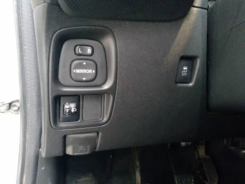 Vue rapprochée des commandes côté gauche du tableau de bord d'une Citroën C1 blanche, réglages des rétroviseurs et contrôle de stabilité.