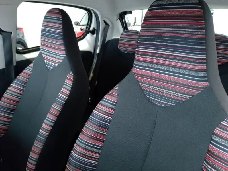 Gros plan sur les sièges avant rayés rouge, gris et noir de la Citroën C1 blanche, vue intérieure côté droit.