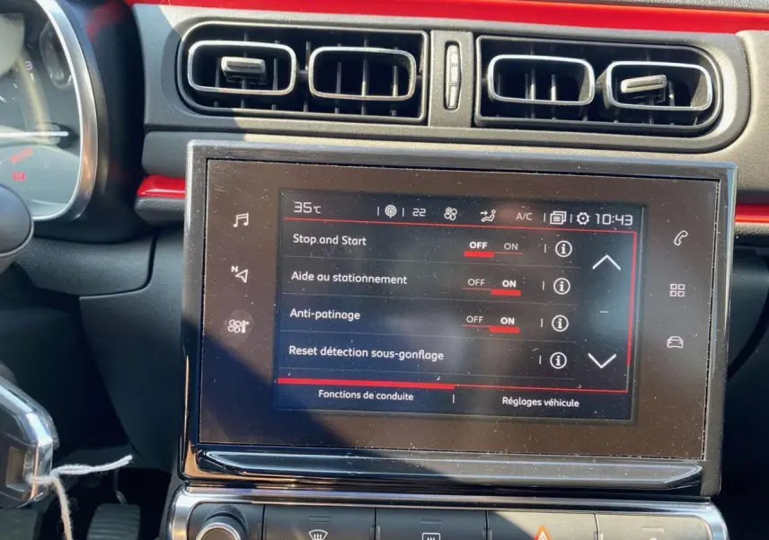 Vue rapprochée du tableau de bord de la Citroën C3 orange, mettant en valeur l'écran tactile central avec réglages activés.