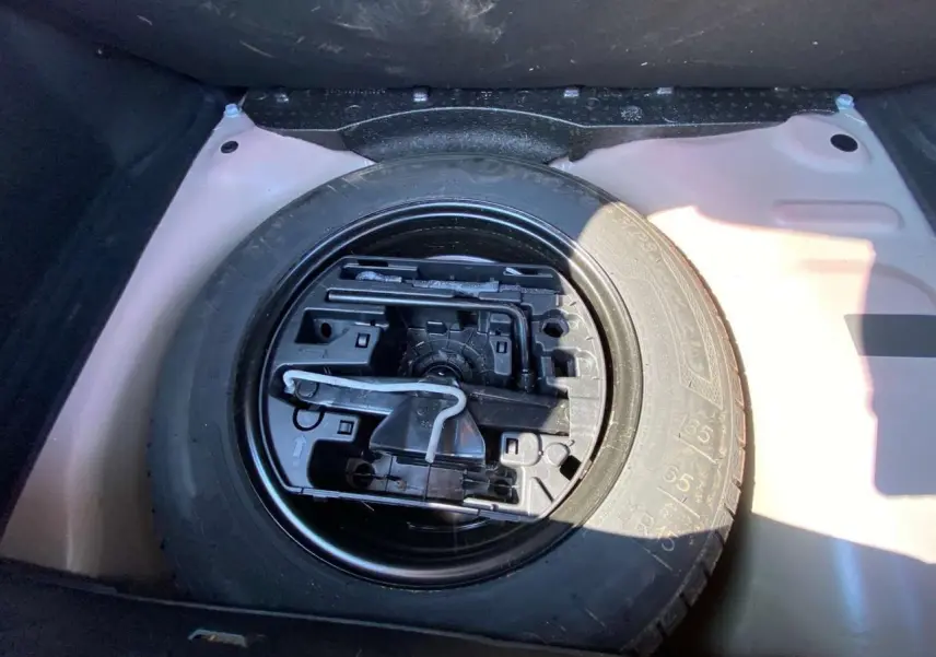 Gros plan sur la roue de secours acier 15 pouces dans le coffre d'une Citroën C3 orange 2018.