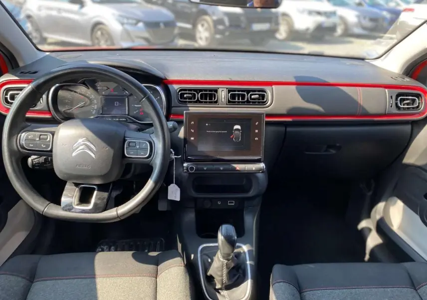 Vue intérieure avant de la Citroën C3 orange 2018, tableau de bord noir avec bande rouge et écran tactile central.