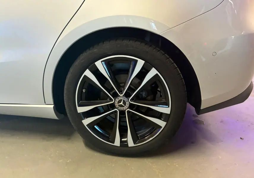 Gros plan sur la roue arrière droite d’une Mercedes Classe B 200D gris, jante alliage noir et argentée.