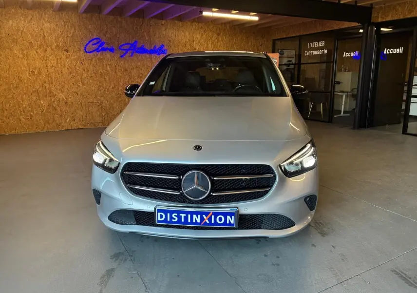 Vue avant d'une Mercedes Classe B 200D Progressive Line gris métallisé, avec calandre noire et logo central lumineux.