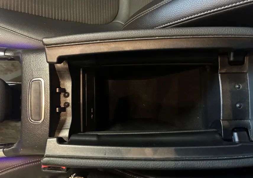 Vue rapprochée de la console centrale ouverte d'une Mercedes Classe B 200D gris, montrant le rangement intérieur et port USB.