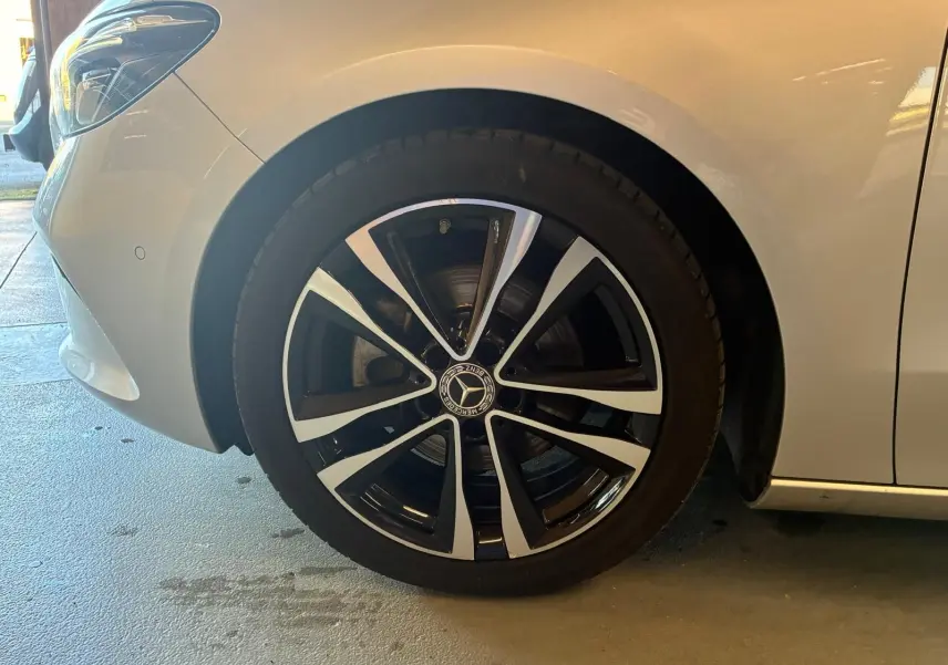 Gros plan sur la roue avant gauche d’une Mercedes Classe B gris clair avec jante alliage noire et argentée.