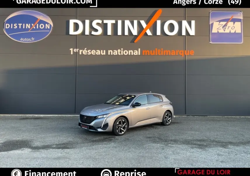 Peugeot 308 gris foncé vue 3/4 avant droit, stationnée devant un mur avec logo Distinxion en arrière-plan.
