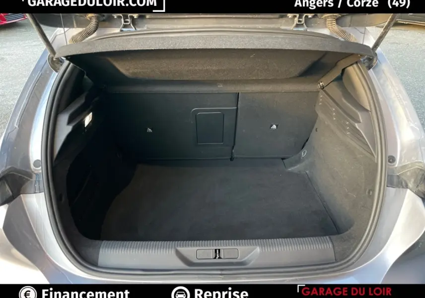 Coffre ouvert vu de l'arrière d'une Peugeot 308 gris foncé 2024, intérieur spacieux et propre sans chargement visible.