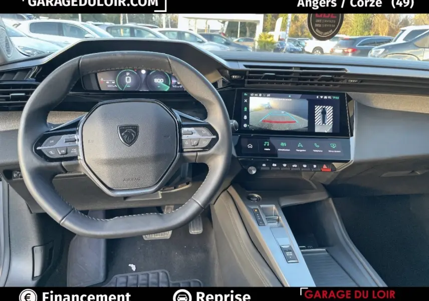 Vue intérieure du poste de conduite de la Peugeot 308 2024 gris foncé, avec volant compact et écran tactile central affichant la caméra de recul.