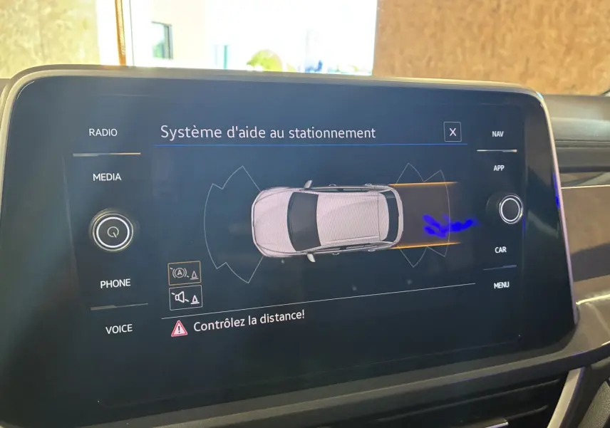 Écran tactile intérieur du Volkswagen T-Roc 2025 affichant le système d'aide au stationnement avec vue du dessus du véhicule.