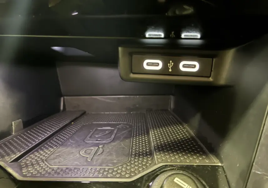 Gros plan sur la zone de recharge sans fil et les deux ports USB-C éclairés du Volkswagen T-Roc noir 2025.